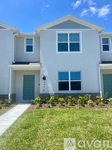 A white two-story house with a blue door and windows.