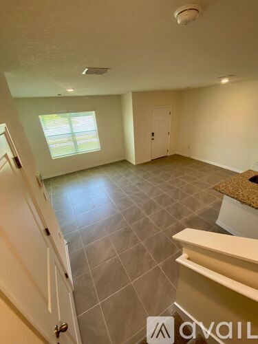 A living room with a tiled floor and a window with blinds.