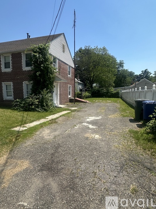 A residential street with a house on the left and a fence on the right.