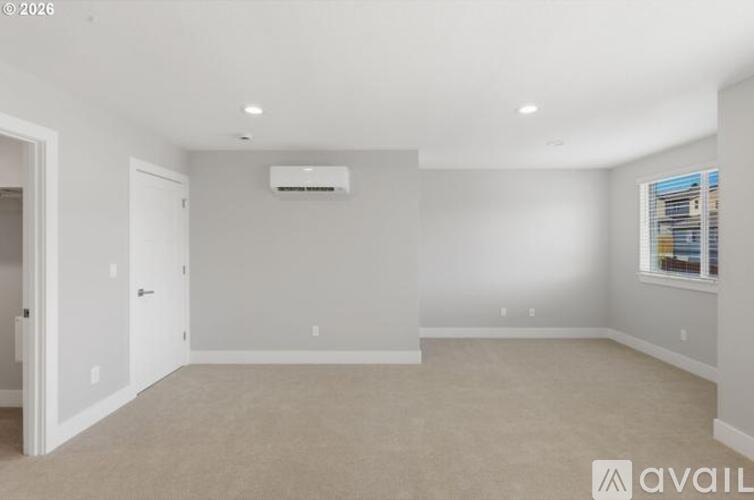 A spacious room with a carpeted floor and a window with blinds.