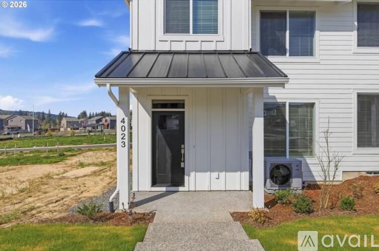 A white house with a black roof and a black door is numbered 4023.
