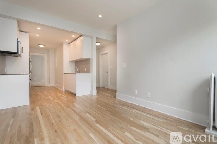 A spacious room with wooden flooring and white walls.