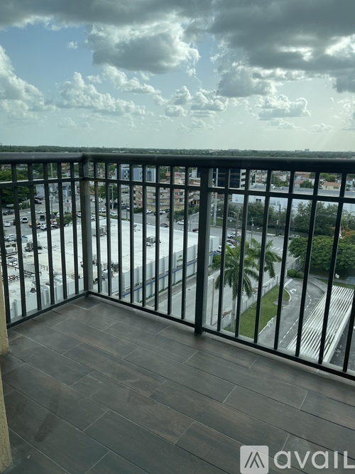 A balcony with a view of a parking lot and buildings.