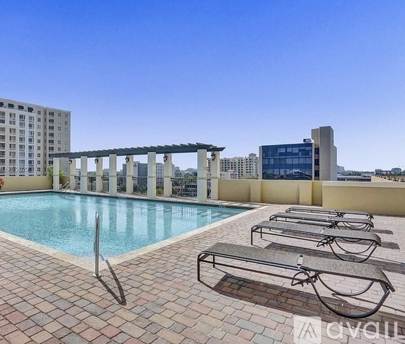 A pool with sun loungers and a building in the background.