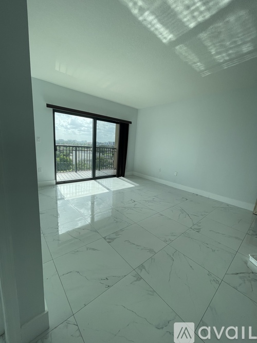 A spacious room with a marble floor and a large window overlooking a balcony.