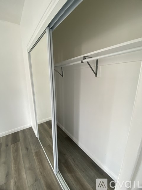 A white closet with a mirror and a shelf.
