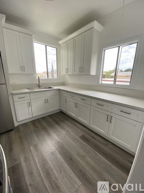 A kitchen with white cabinets and a wooden floor.
