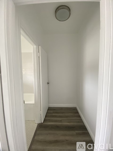 A hallway with a wooden floor and white walls.