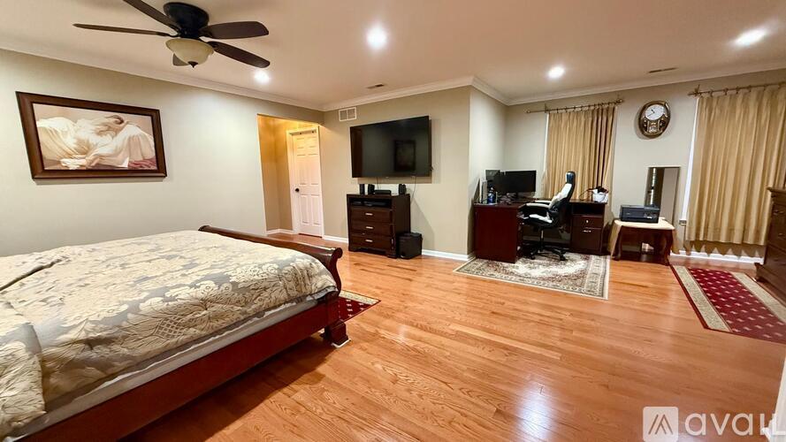 A bedroom with a large bed, a television, and a wooden floor.