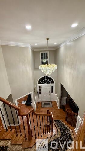 A chandelier hangs from the ceiling in a spacious foyer with a staircase.