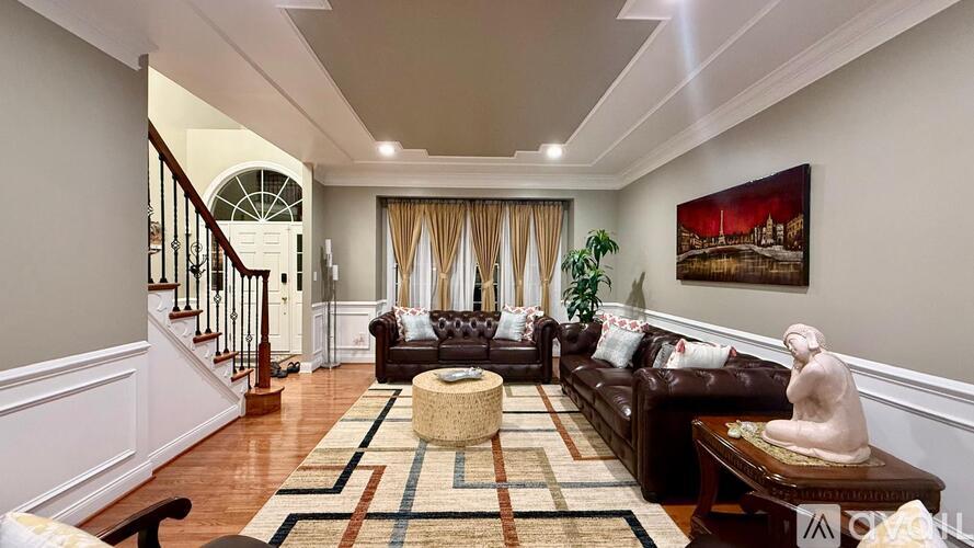 A living room with a brown couch and a painting on the wall.