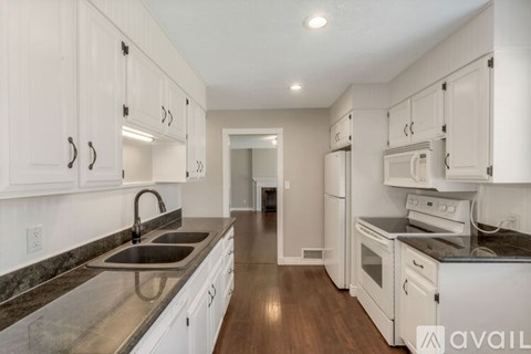 A kitchen with white cabinets and a black countertop.
