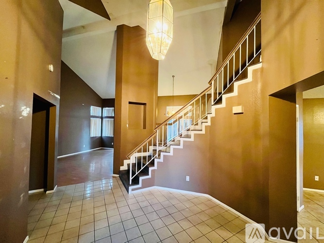 A large, empty foyer with a staircase and a chandelier.