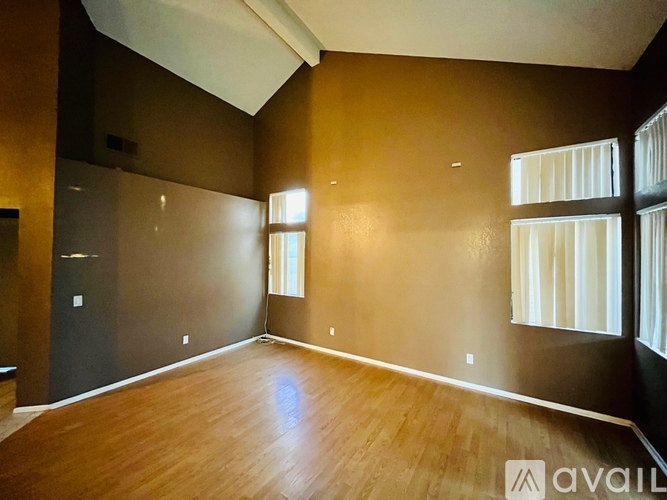 A spacious room with wooden floors and a large window.