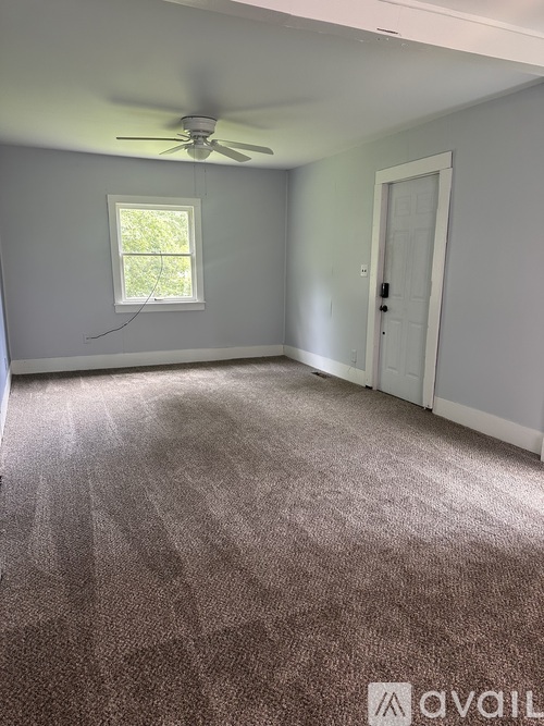 A room with a ceiling fan and carpeted floor.