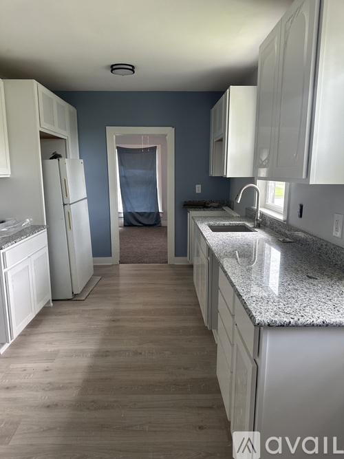 A kitchen with white cabinets and a marble countertop.