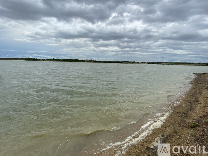 A body of water with a cloudy sky above and a rocky shore in the foreground.