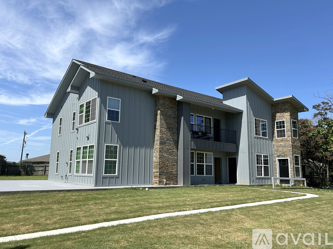 A modern house with a grey exterior and a stone wall.