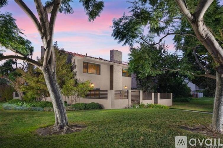 A modern house with a large front yard and trees.
