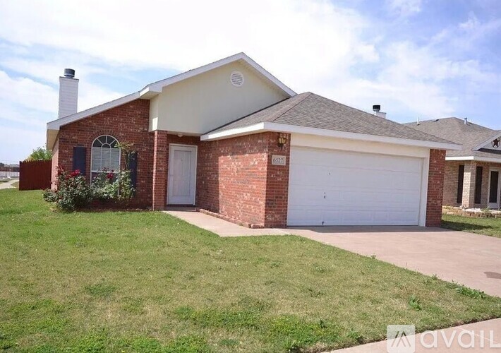 A brick house with a white garage door and a window with a flower pot on the windowsill.