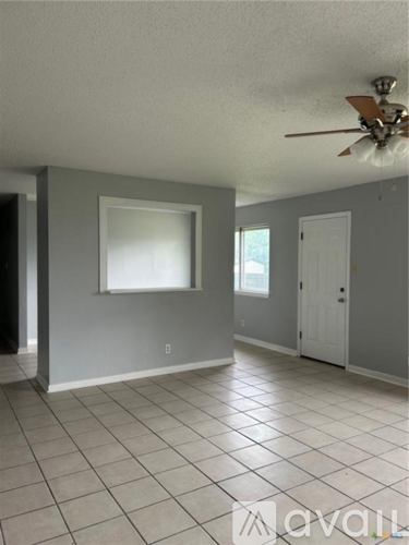 A spacious room with a ceiling fan and tiled flooring.