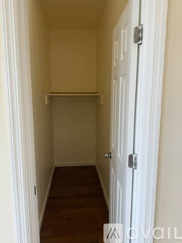 A hallway with a white door and a wooden floor.