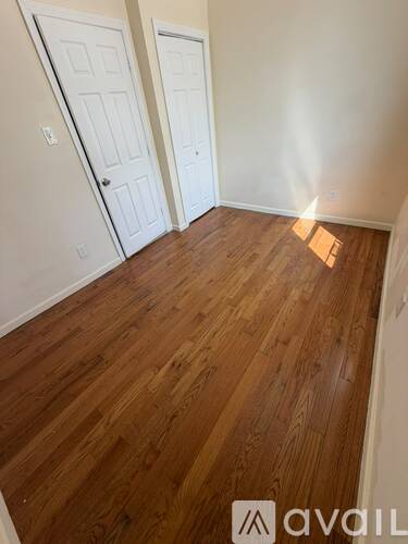 A room with wooden flooring and two white doors.