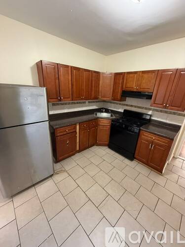 A kitchen with a stainless steel refrigerator and black stove top oven.