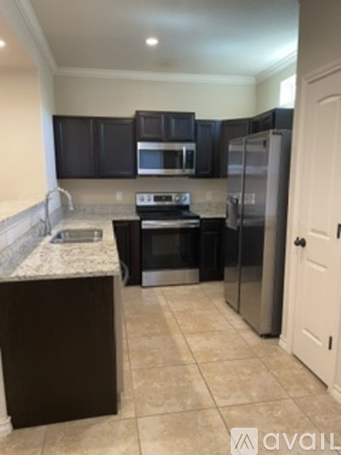 A kitchen with dark brown cabinets and a white door.