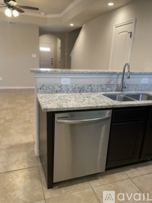 A kitchen with a marble countertop and a stainless steel dishwasher.