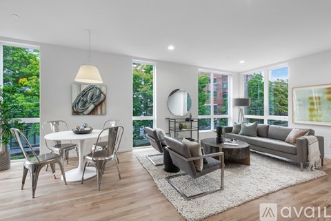 A modern living room with a white dining table and grey sofa.