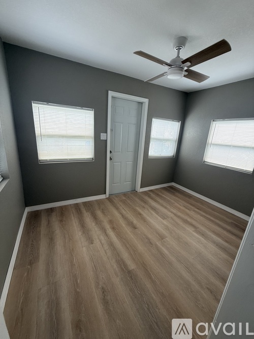 A room with a ceiling fan and wooden flooring.
