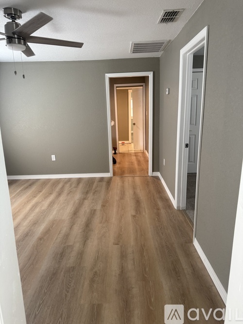 A room with a ceiling fan and wooden flooring.