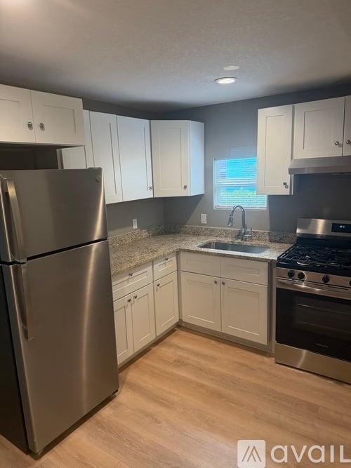 A kitchen with a stainless steel refrigerator and wooden floors.