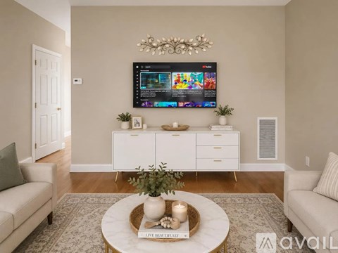 A living room with a television mounted on the wall and a coffee table in the center.