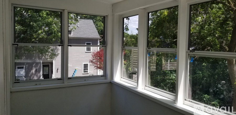 A white window with a view of a house and trees outside.