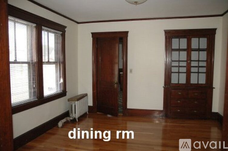 A dining room with a wooden floor and a white radiator.