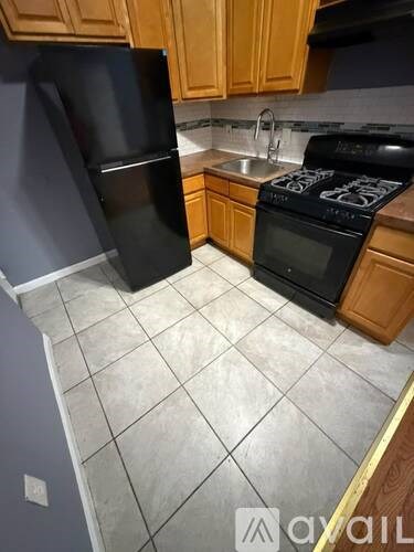 A kitchen with a black refrigerator and black stove top oven.
