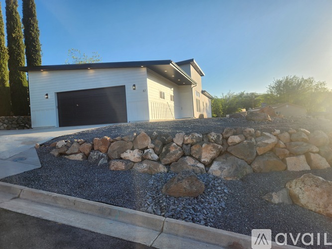 A modern house with a stone and gravel driveway in front.