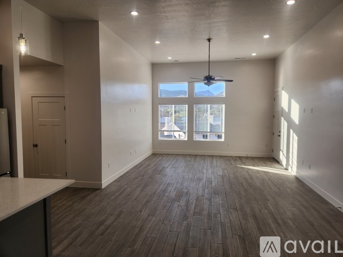 A spacious room with wooden flooring and a ceiling fan.