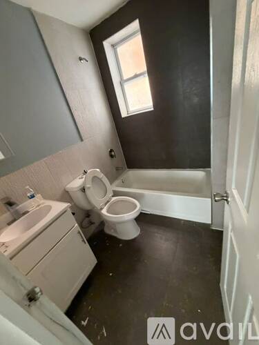 A bathroom with a toilet, sink, and a window.