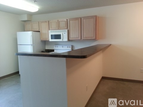 A kitchen with a white refrigerator, a white microwave, and wooden cabinets.