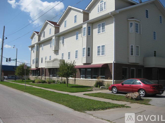 A red car is parked on the side of a street in front of a building.