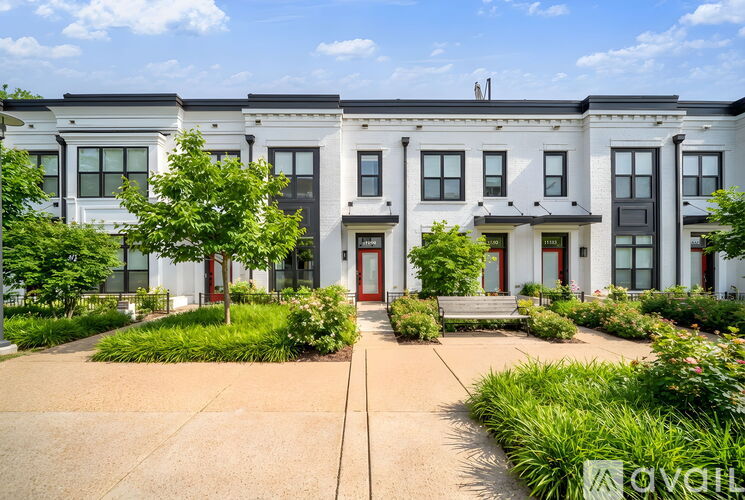 A row of townhouses with a front yard and a bench.