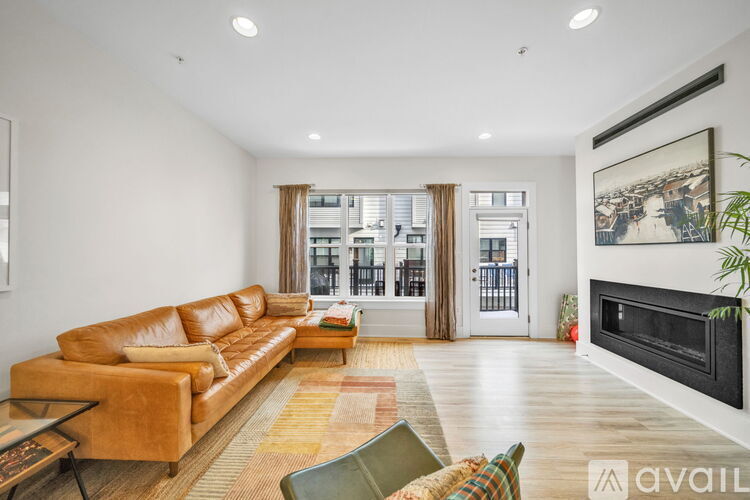 A living room with a brown leather couch and a fireplace.