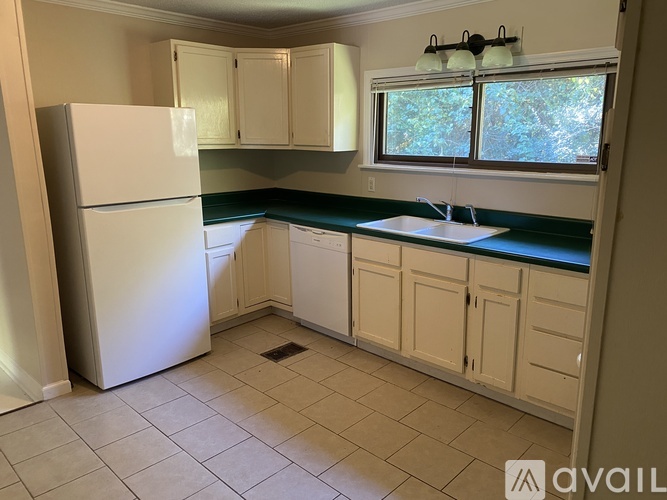A kitchen with a white refrigerator and cabinets.