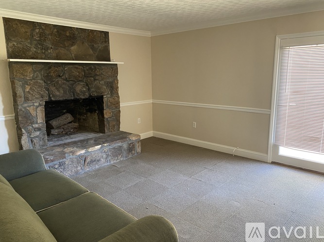 A living room with a stone fireplace and a grey couch.