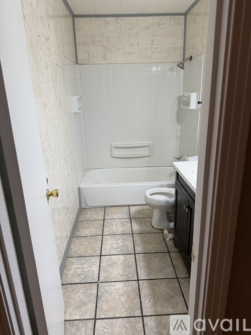 A bathroom with a toilet, tub, and tiled floor.
