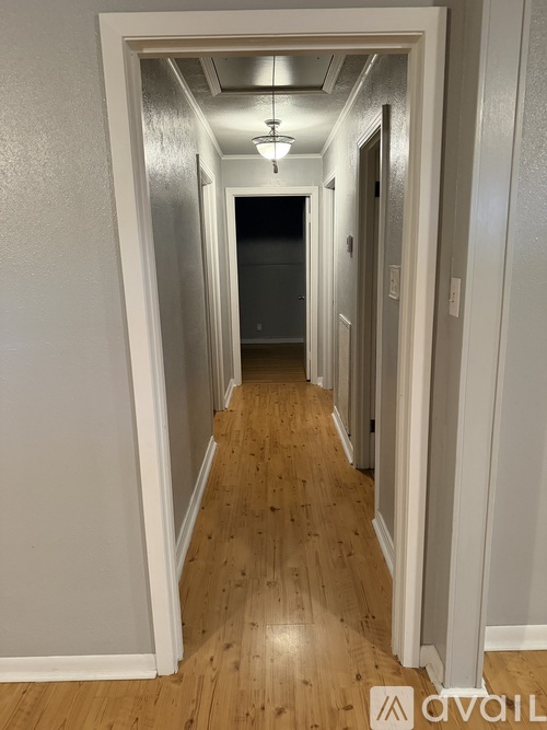 A hallway with wooden floors and white walls.