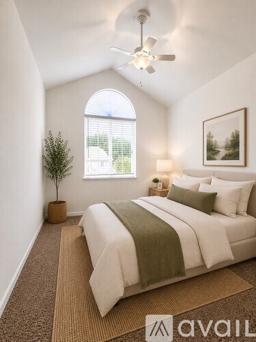 A bedroom with a large bed and a ceiling fan.